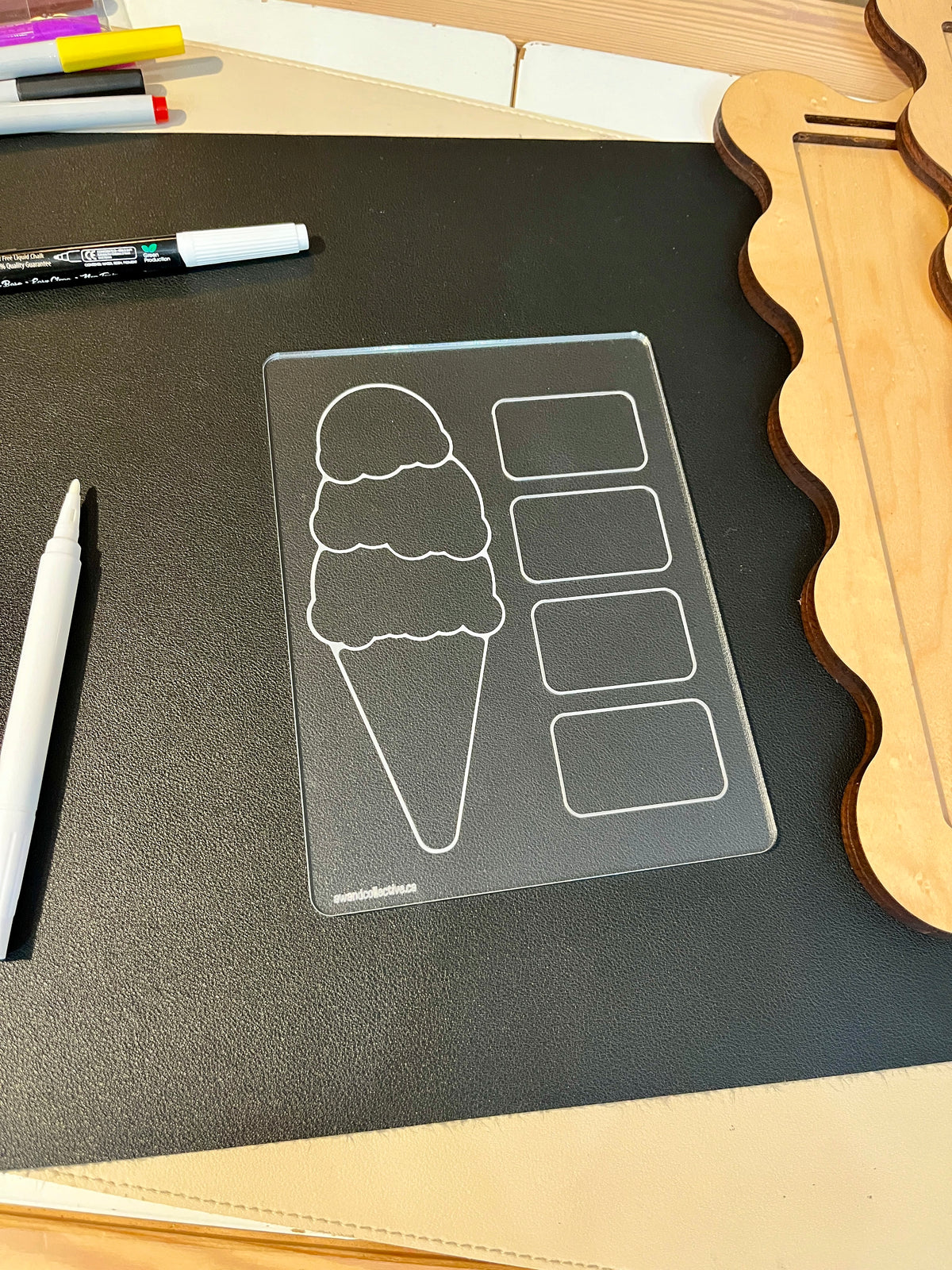Clear acrylic board with ice cream cone and four rectangular sections on black mat beside white markers and wooden shapes