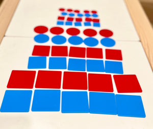 Red and blue flat circular and square plastic tiles stacked in alternating rows on a white surface with a wooden frame