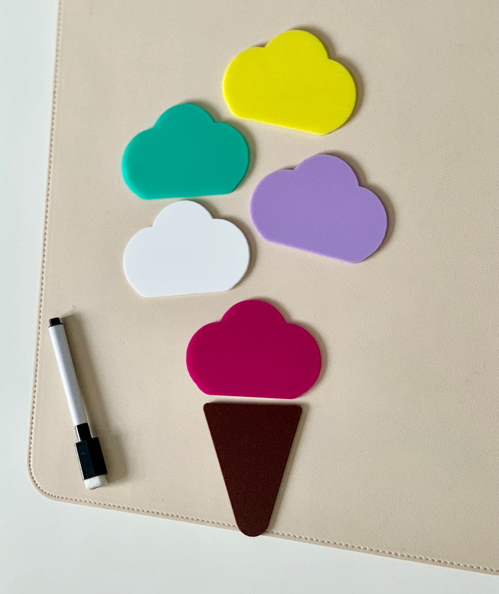 Five colorful cloud-shaped pieces and a brown triangle arranged on a beige surface next to a black marker