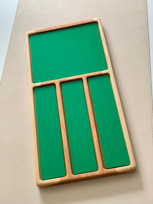 Wooden organizer tray with one large square and three narrow rectangular green panels on a beige surface