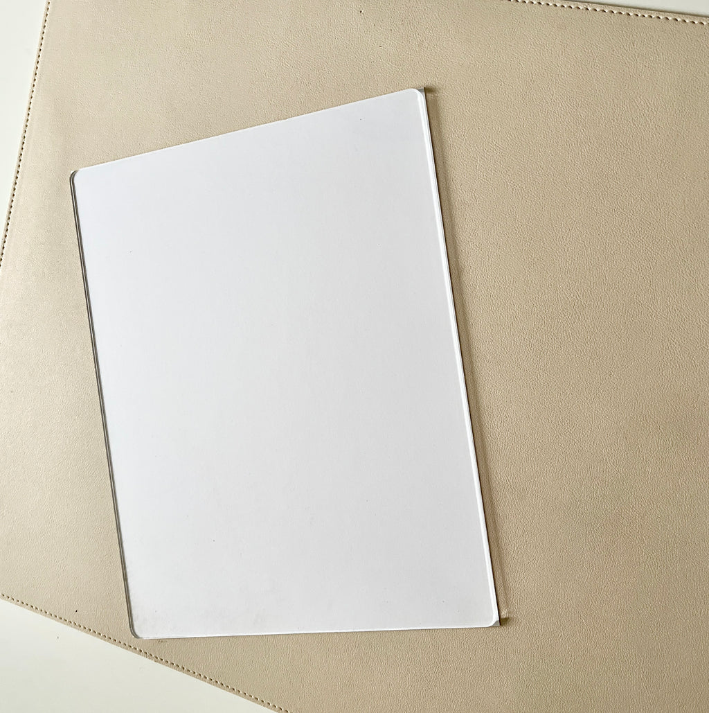 Clear rectangular acrylic or plastic sheet resting on a textured beige surface with soft lighting