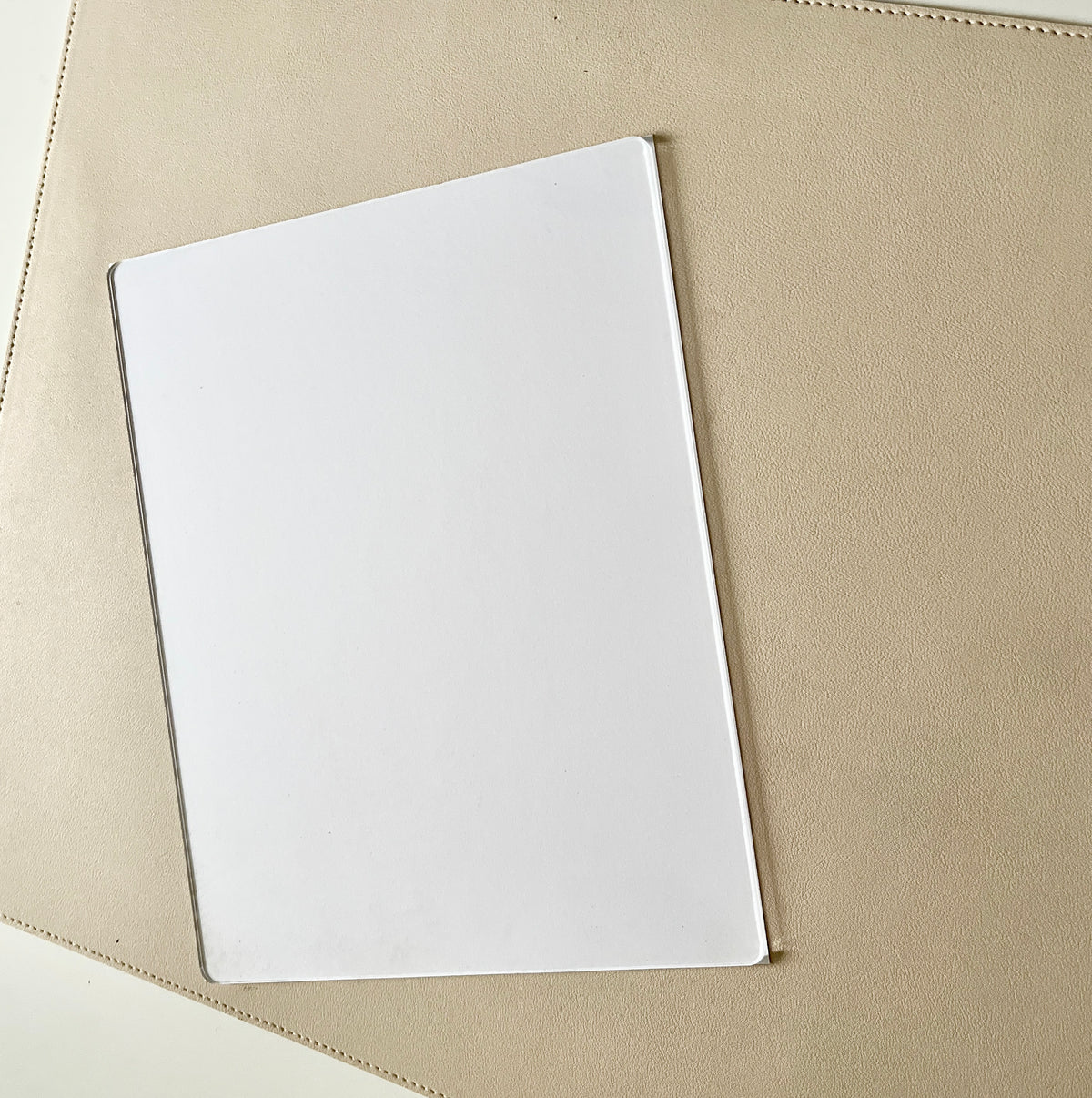 Clear rectangular acrylic or plastic sheet resting on a textured beige surface with soft lighting