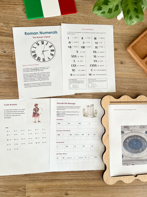 Digital Download | Roman Numerals, Their History & DeCoding Activity featuring printed educational pages with Roman numeral charts, decoding exercises, and a wooden tray on a natural wood surface, handcrafted, homeschool, education resources.