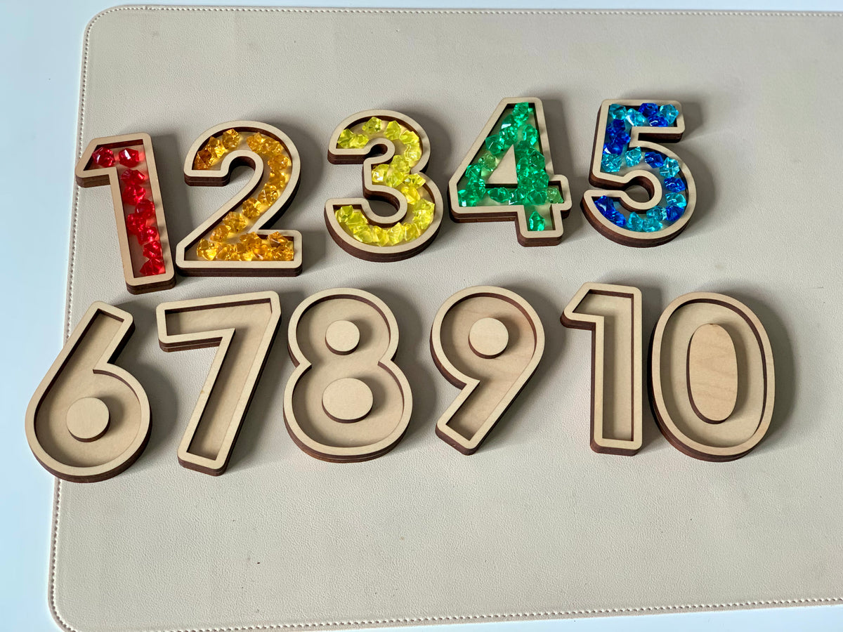 Wooden number cutouts 1 to 5 filled with colorful beads and plain wooden numbers 6 to 10 on light surface