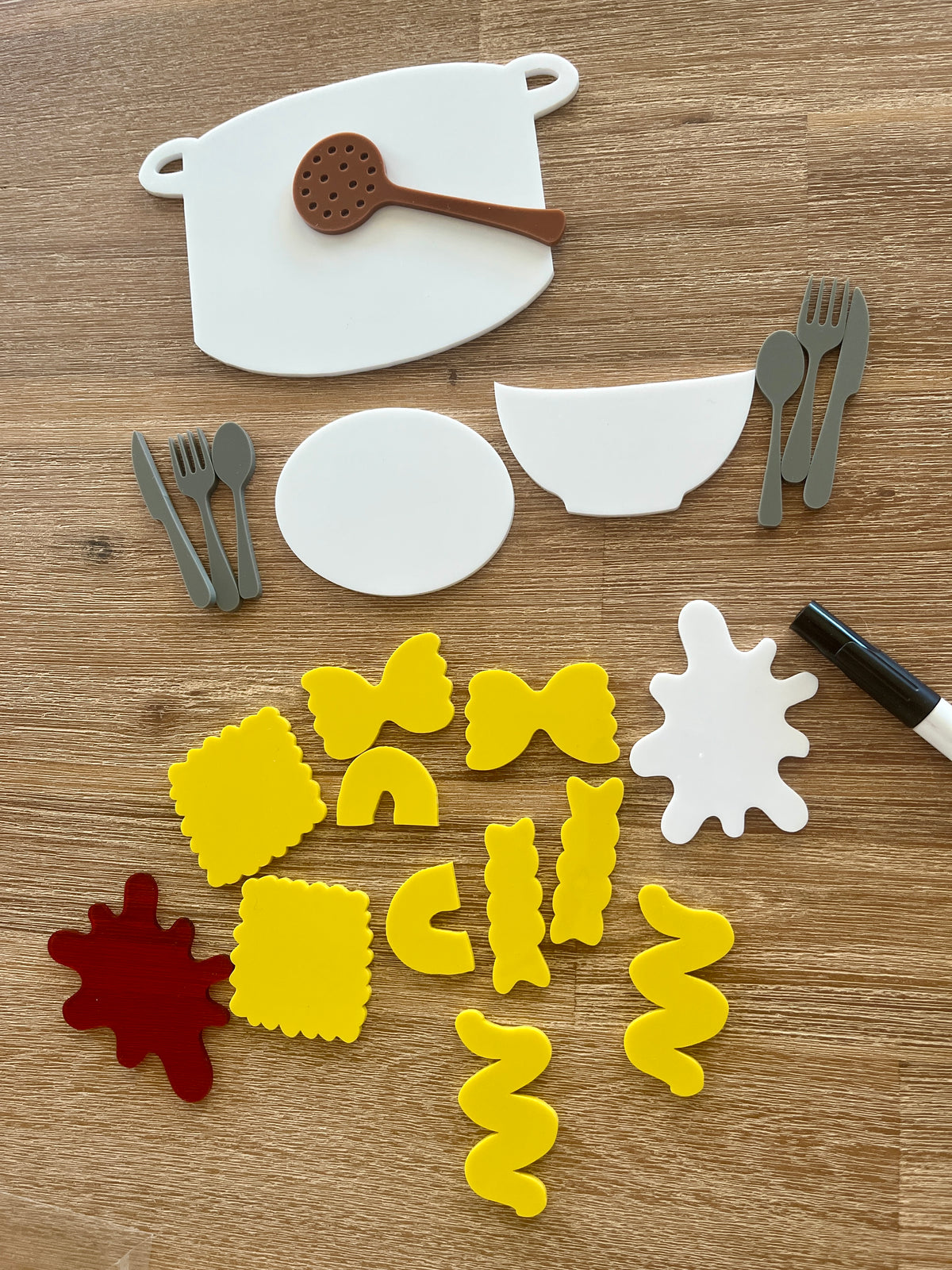 Little Dry Erasables - Pasta with Sauce, Pot, Plate, Bowl and Cutlery featuring handcrafted wooden shapes of pasta varieties, cooking pot, white bowl, utensils, red and white sauce pieces, and a black marker, homeschool education resources.