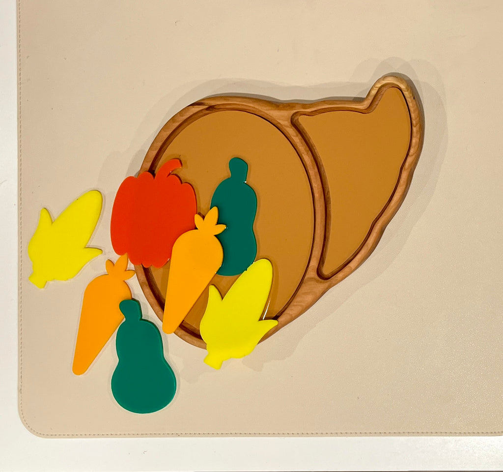 Wooden turkey-shaped puzzle board with colorful foam vegetable and fruit pieces scattered on a beige surface