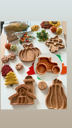 Wooden trays shaped like pumpkin, scarecrow, tractor, barn, and autumn trees surrounded by felt pumpkins and craft supplies