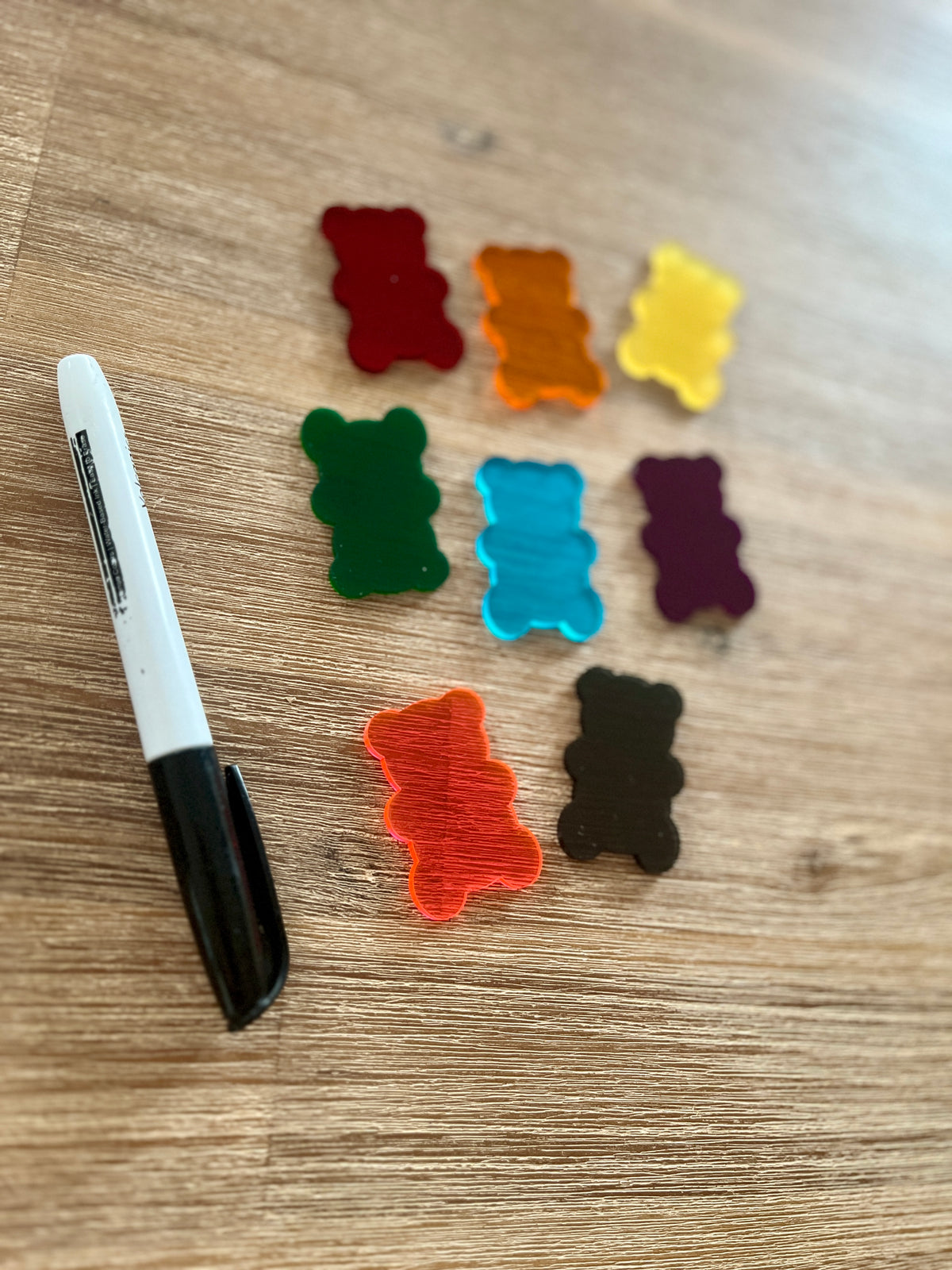 Little Dry Erasables — Gummy Bears featuring translucent colorful gummy bear shapes in various shades arranged on a wooden surface with a black marker, handcrafted homeschool education resources.