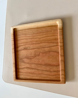 Square wooden tray with natural grain on light beige textured surface