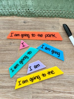 Little Dry Erasable Sentence Building Pyramid; Fluency Triangle pieces in various colors arranged on wood surface with black dry erase marker and green textured fabric, handcrafted homeschool education resources.