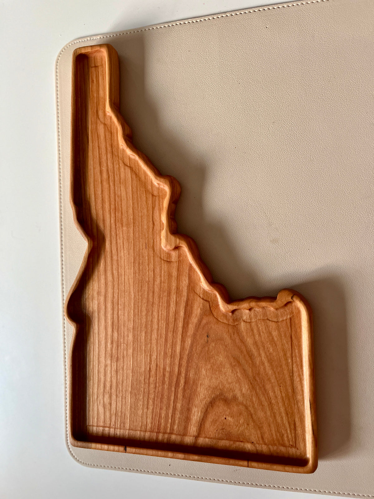 Smooth wooden tray crafted in the shape of Idaho with visible wood grain on a light surface