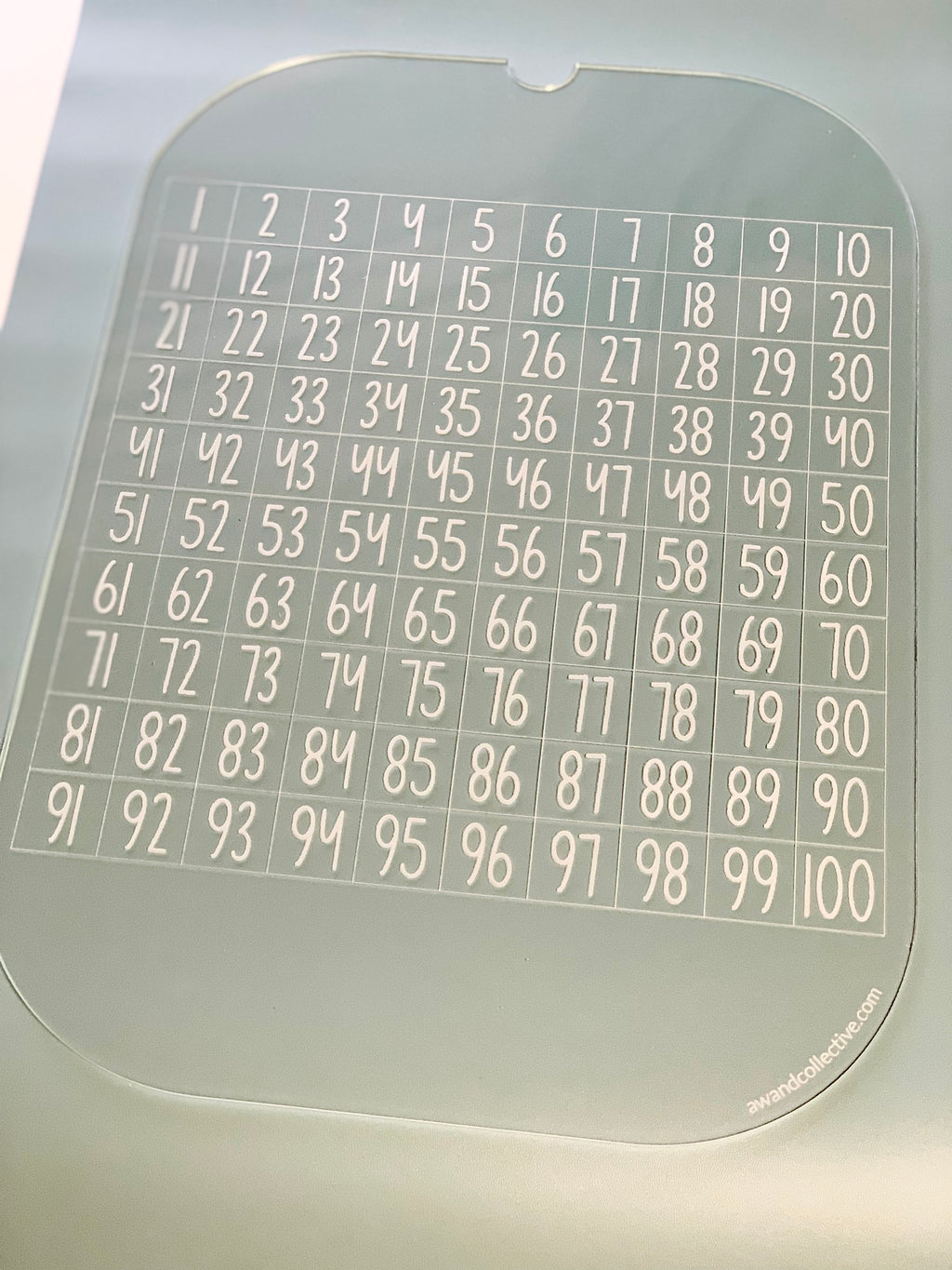 Clear acrylic sheet featuring numbers from 1 to 100 arranged in a grid pattern with ten columns and ten rows