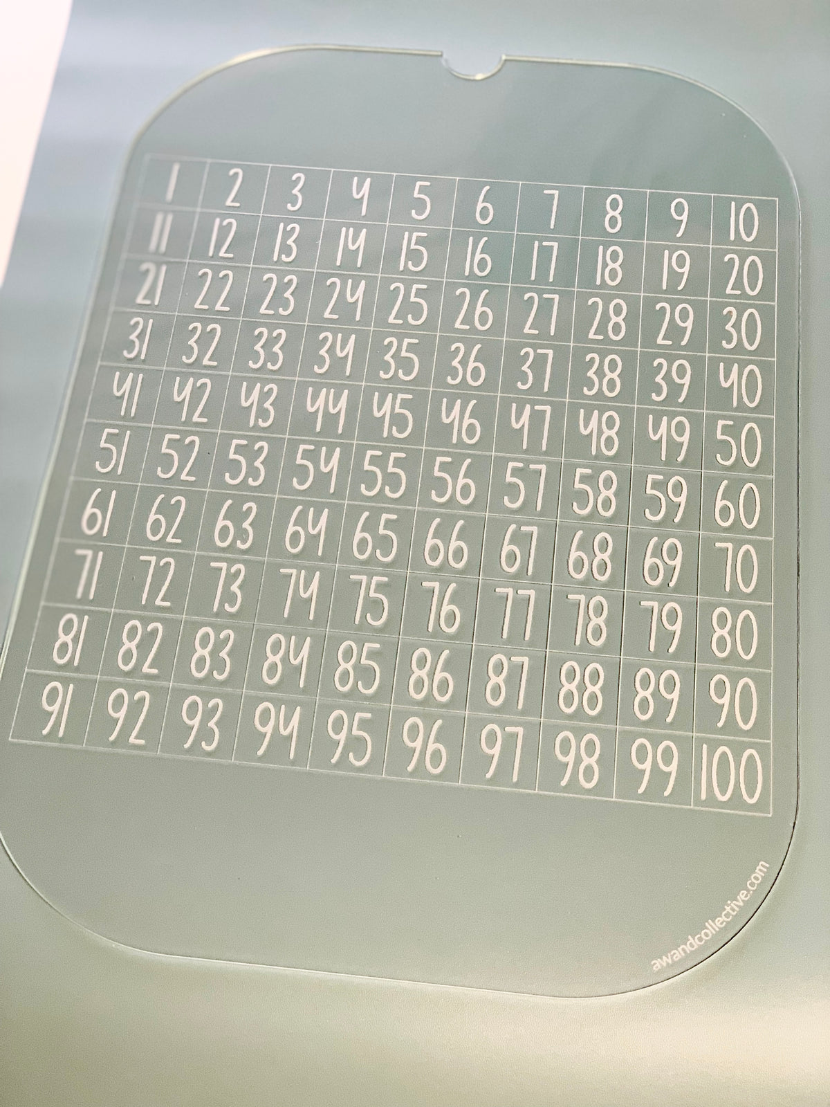 Clear acrylic sheet featuring numbers from 1 to 100 arranged in a grid pattern with ten columns and ten rows