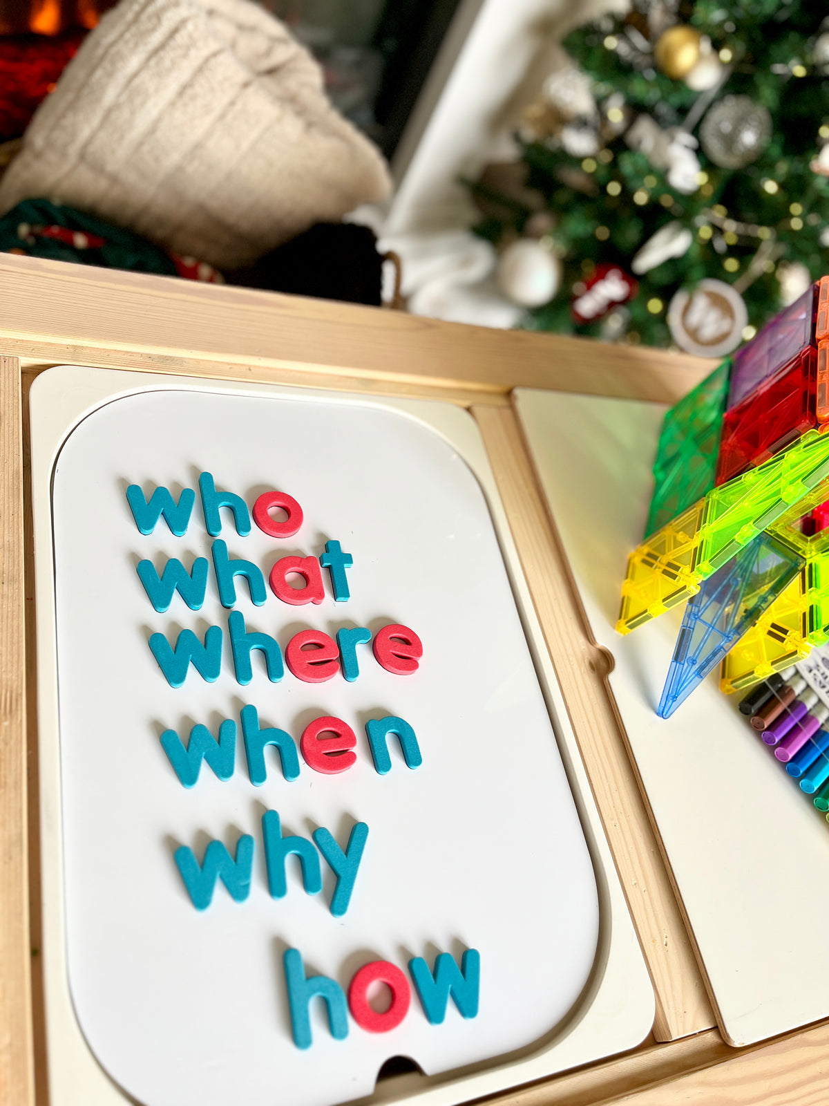 Colorful magnetic letters spelling question words arranged on white magnetic board beside translucent building blocks and markers