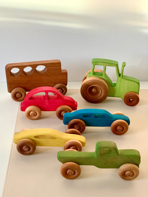 Set of six colorful wooden toy vehicles including a bus, tractor, and various cars on a light surface