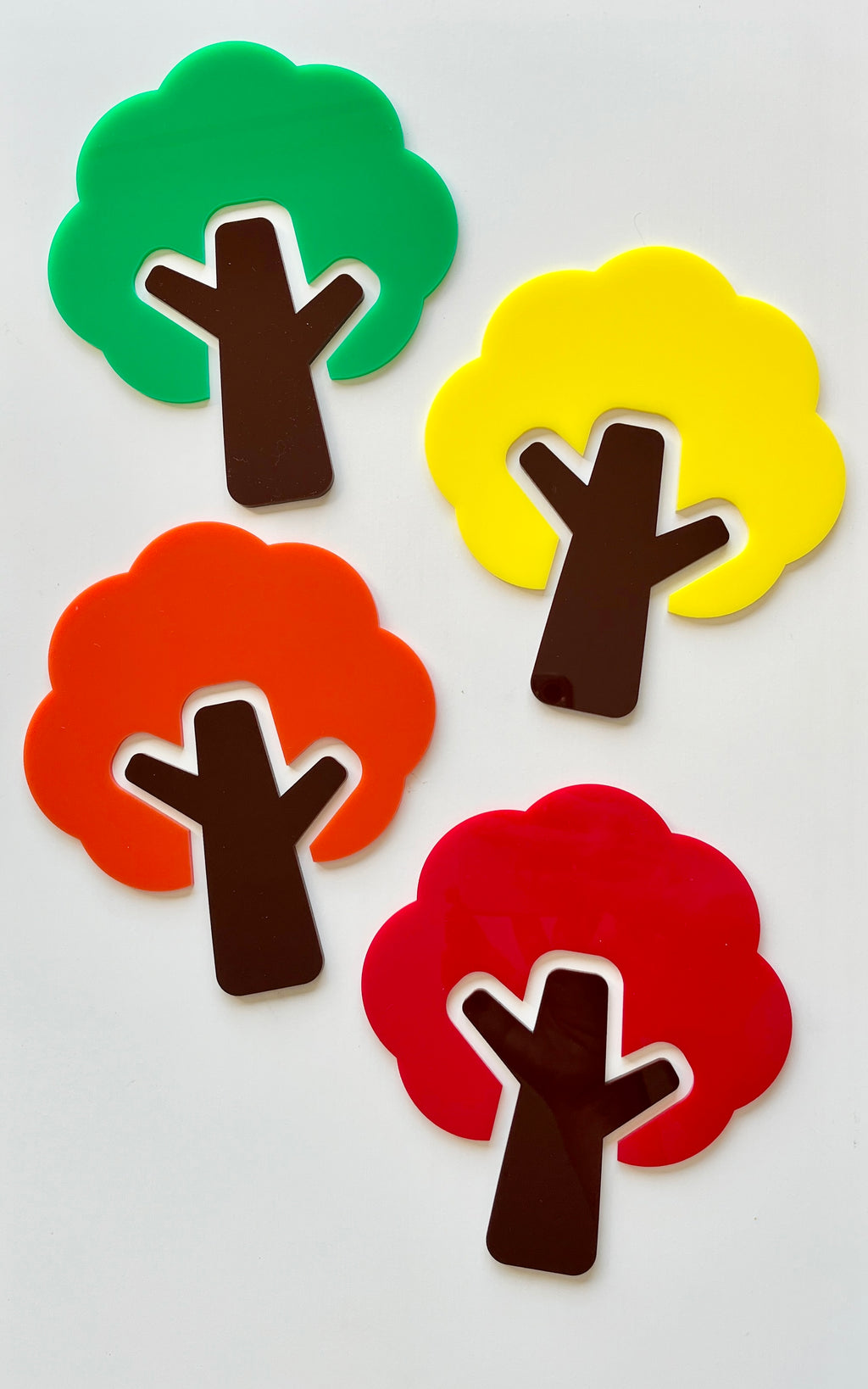 Set of four colorful stylized tree shapes in green, yellow, orange, and red with dark brown trunks on white background