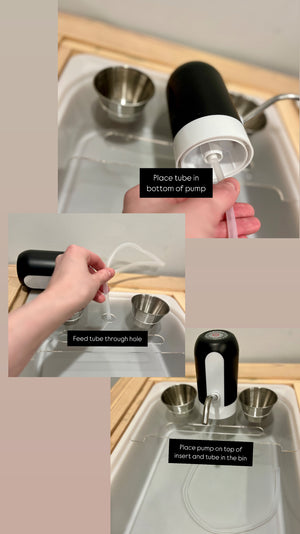 Black and white play kitchen water pump with clear tube installed on wooden sink insert with metal bowls