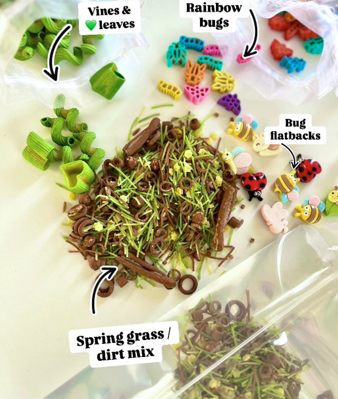 Assorted colorful bug-shaped pieces, green vine shapes, and brown spring grass mix scattered on white surface