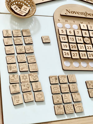 Wooden perpetual calendar with month name, date tiles, and various engraved holiday and event marker tiles on white surface