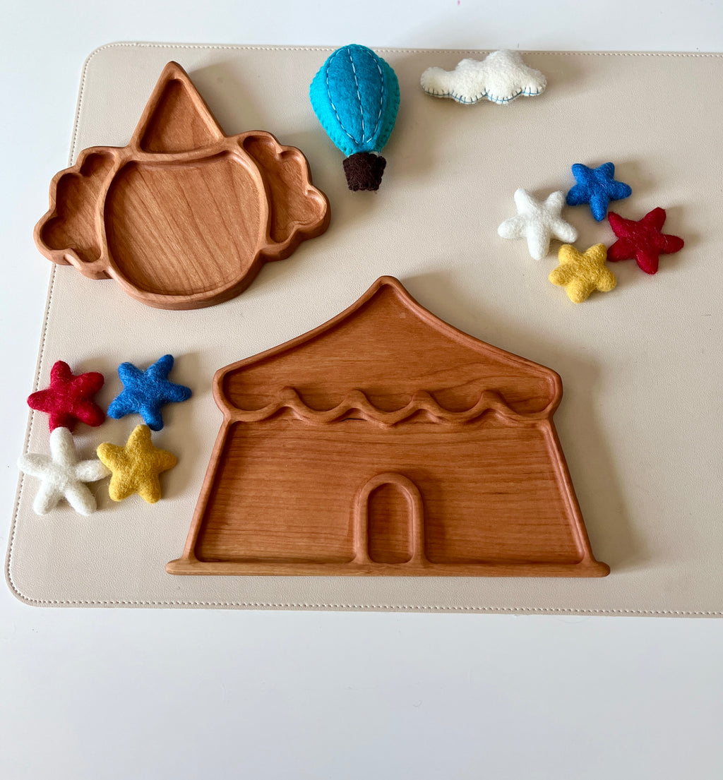 Wooden trays shaped like a circus tent and clown face surrounded by felt stars, a cloud, and a hot air balloon toy
