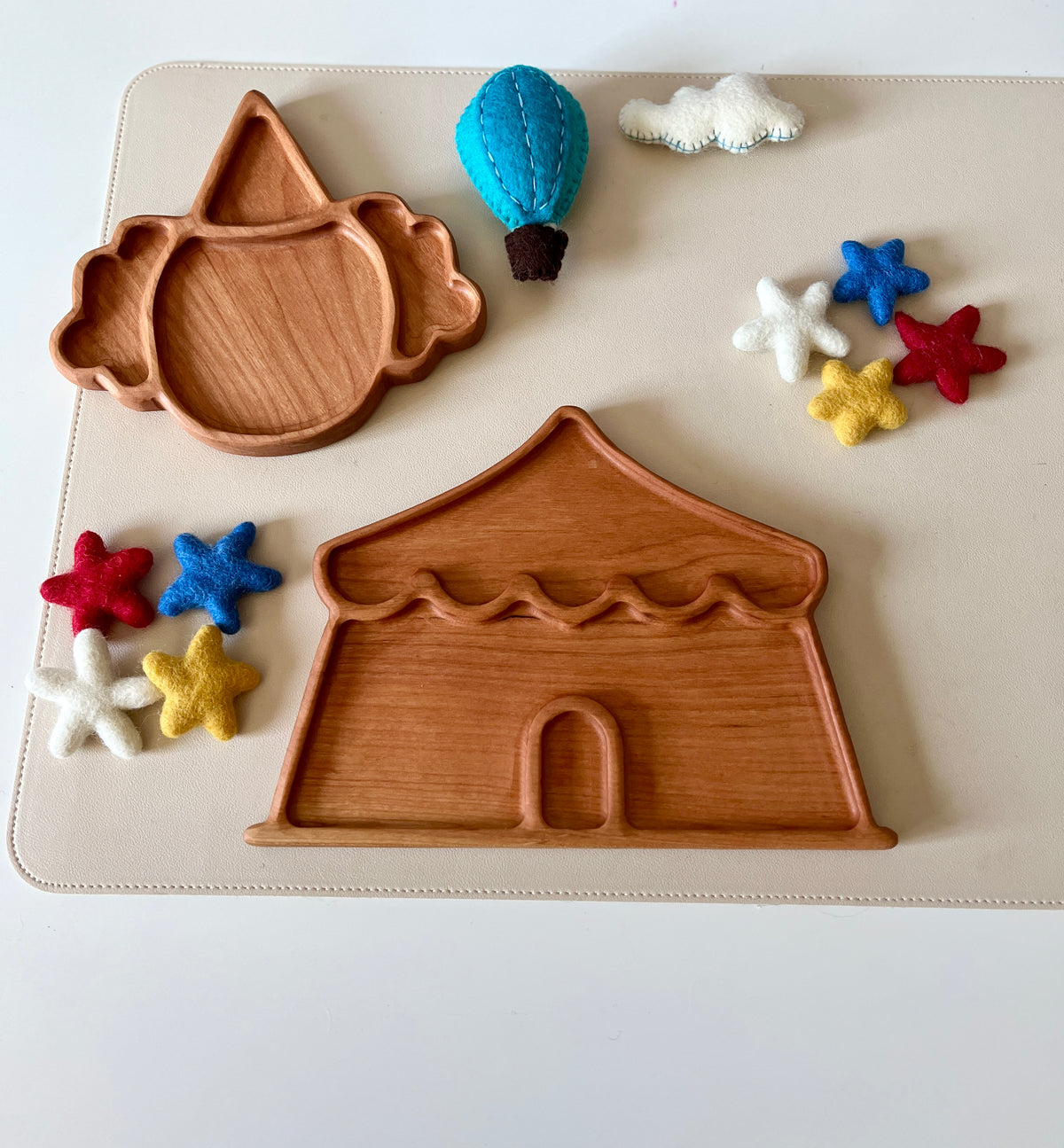 Wooden trays shaped like a circus tent and clown face surrounded by felt stars, a cloud, and a hot air balloon toy