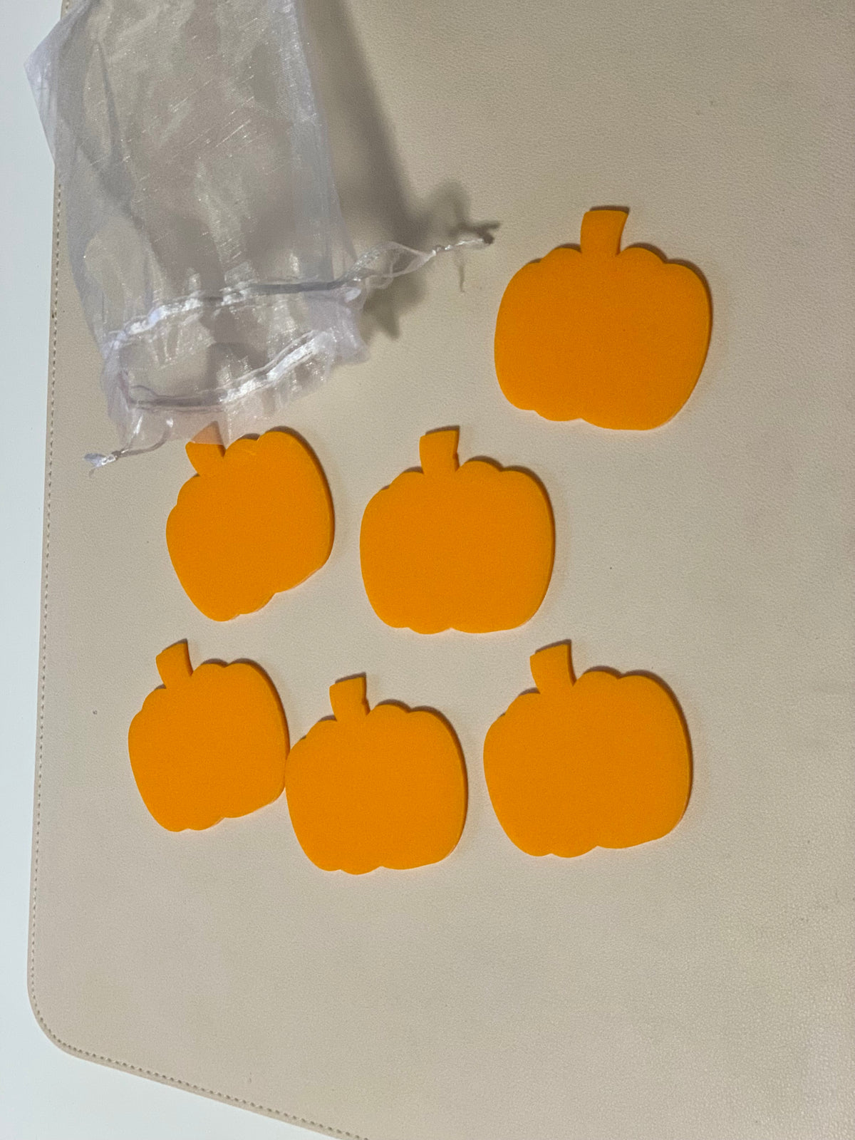 Set of six orange pumpkin-shaped dry erase boards with a sheer white drawstring storage bag on beige surface