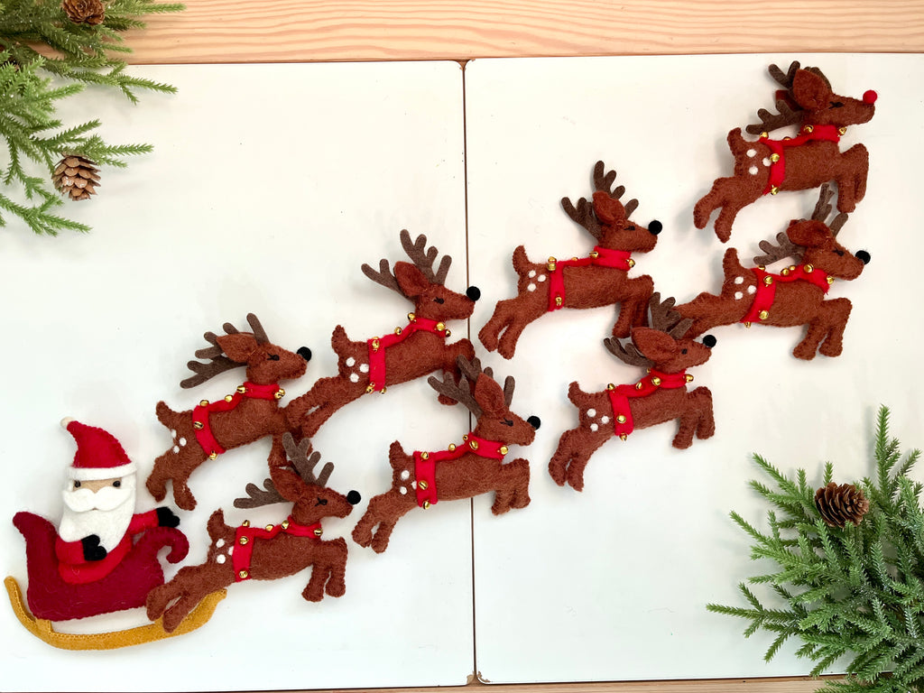 Felt Santa riding red sleigh pulled by nine brown reindeer with red collars and gold bells on white boards