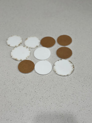 Assorted round coasters in white felt and brown wood arranged on a light speckled surface