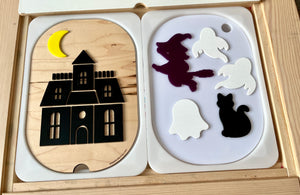 Wooden puzzle with a black haunted house under a yellow crescent moon and separate pieces of witch, ghosts, and black cat