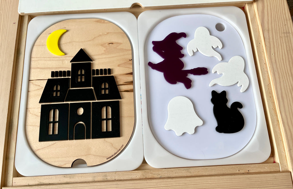 Wooden puzzle with a black haunted house under a yellow crescent moon and separate pieces of witch, ghosts, and black cat