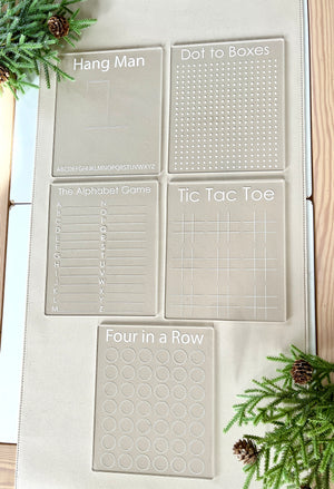 Set of five clear acrylic game boards for Hangman, Dot to Boxes, Alphabet Game, Tic Tac Toe, and Four in a Row on a beige mat