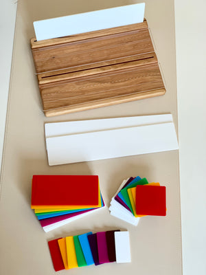 Wooden writing tray with clear dry erase cover, white language boards, and colorful plastic shaped cards on beige surface