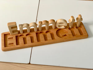 Personalized hardwood name puzzle with natural wood letters spelling Emmett on matching wooden base tray