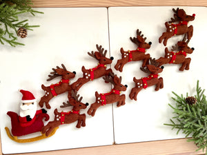 Felt Santa figure in red sleigh being pulled by eight brown felt reindeer with red collars and bells on white surface