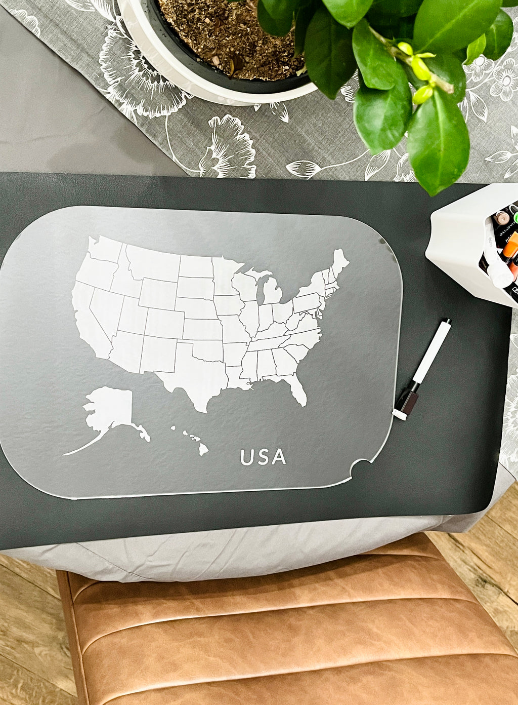 Clear acrylic board etched with a detailed USA map and state borders next to a black dry erase marker on a table