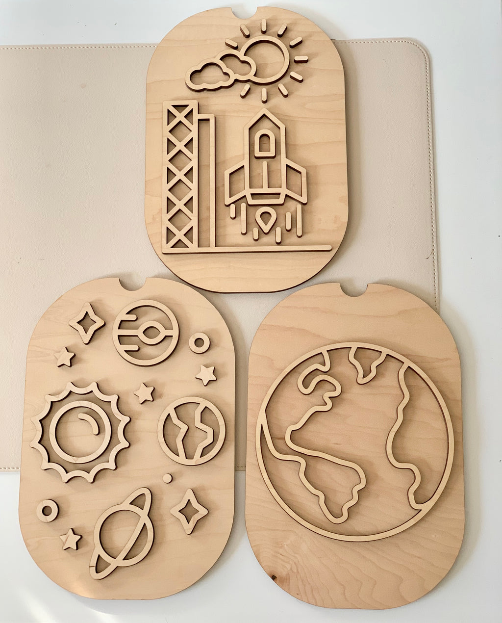 Set of three wooden puzzles depicting a rocket launch, solar system, and Earth outline on a light background
