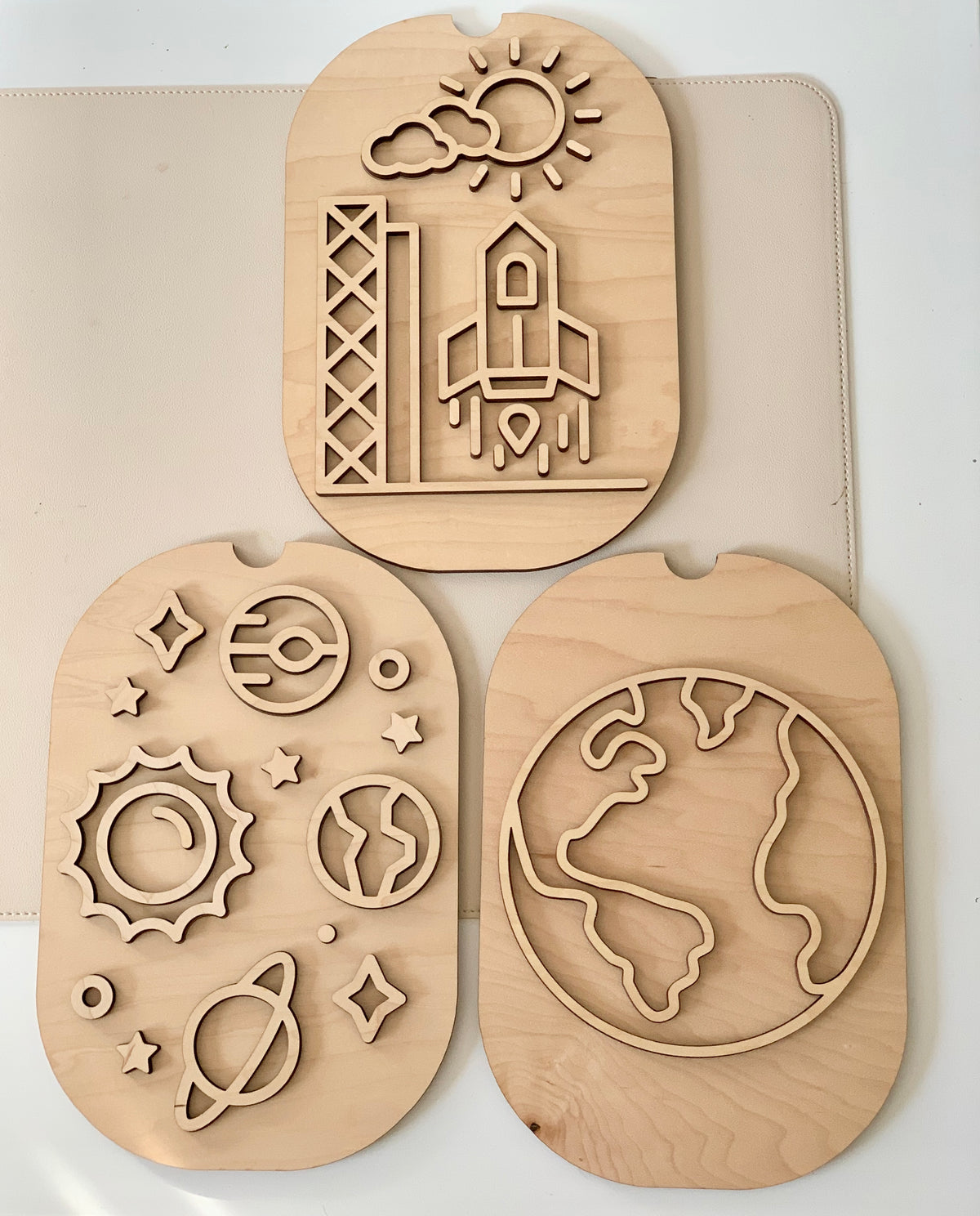 Set of three wooden puzzles depicting a rocket launch, solar system, and Earth outline on a light background