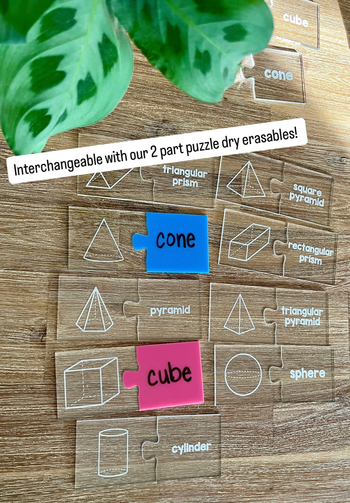Little Dry Erasables - 2 Part Geometry 3D Shape Puzzles showing clear puzzle pieces with white geometric shape illustrations paired with colorful dry erase labels on a wood table, handcrafted homeschool education resources.