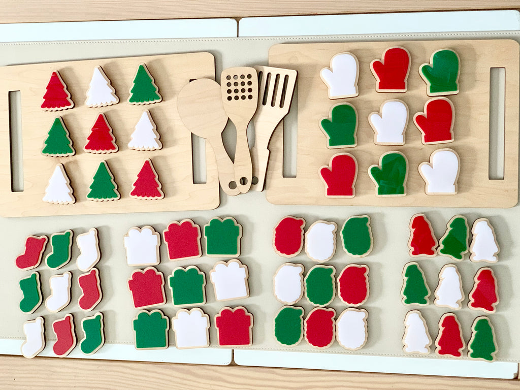 Wooden cookie sheet with red, green, and white felt cookies and matching wooden utensils on a white table