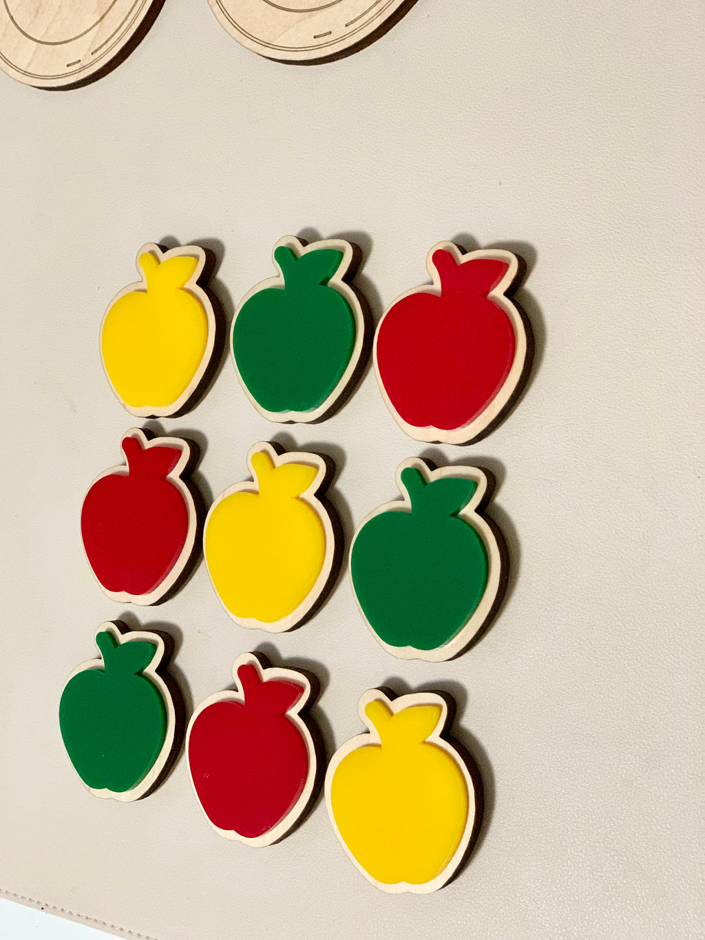 Wooden cookie-shaped pieces in red, green, and yellow with velcro backing on white surface