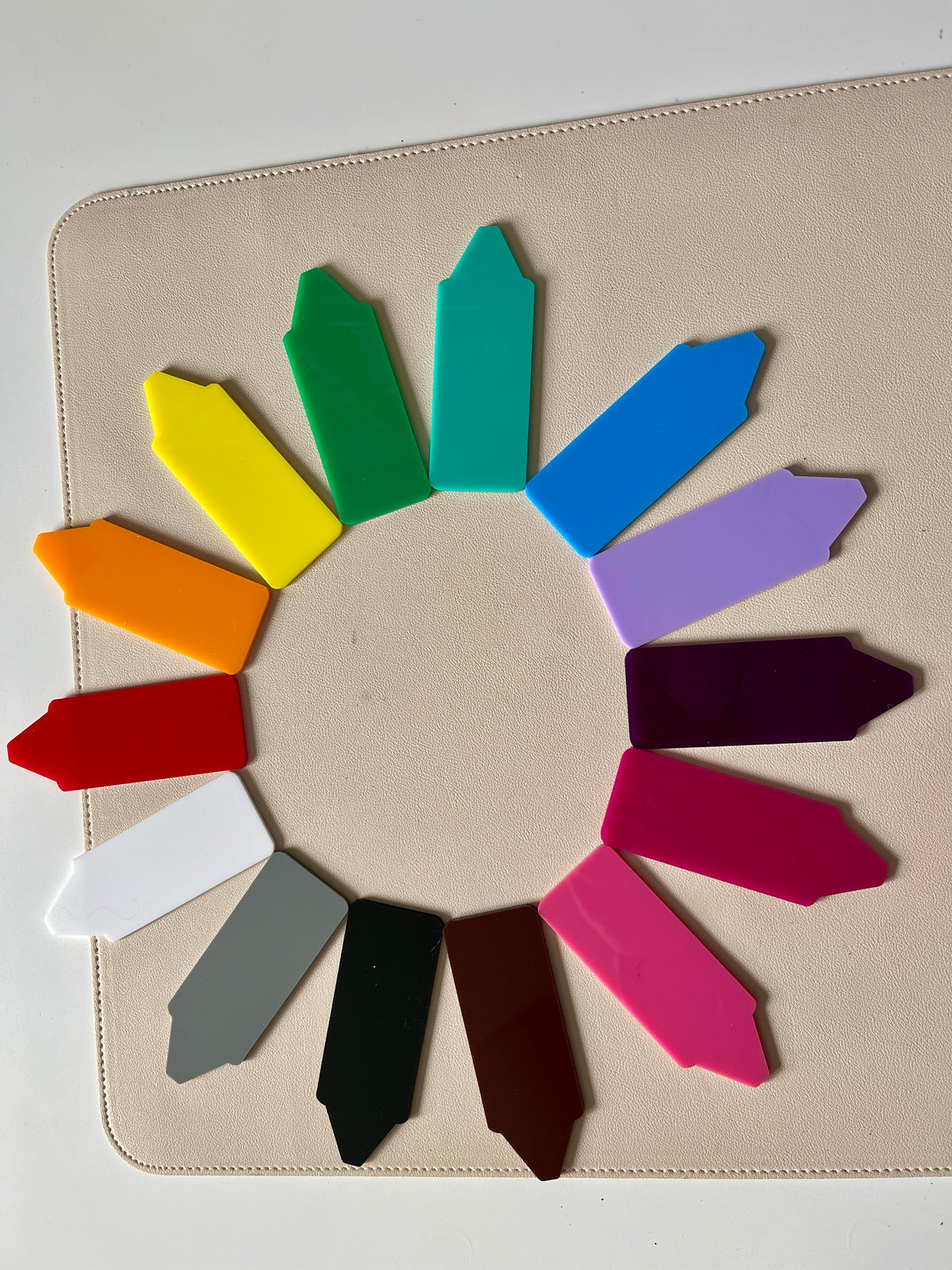 Colorful plastic plant markers arranged in a circular pattern on a beige surface