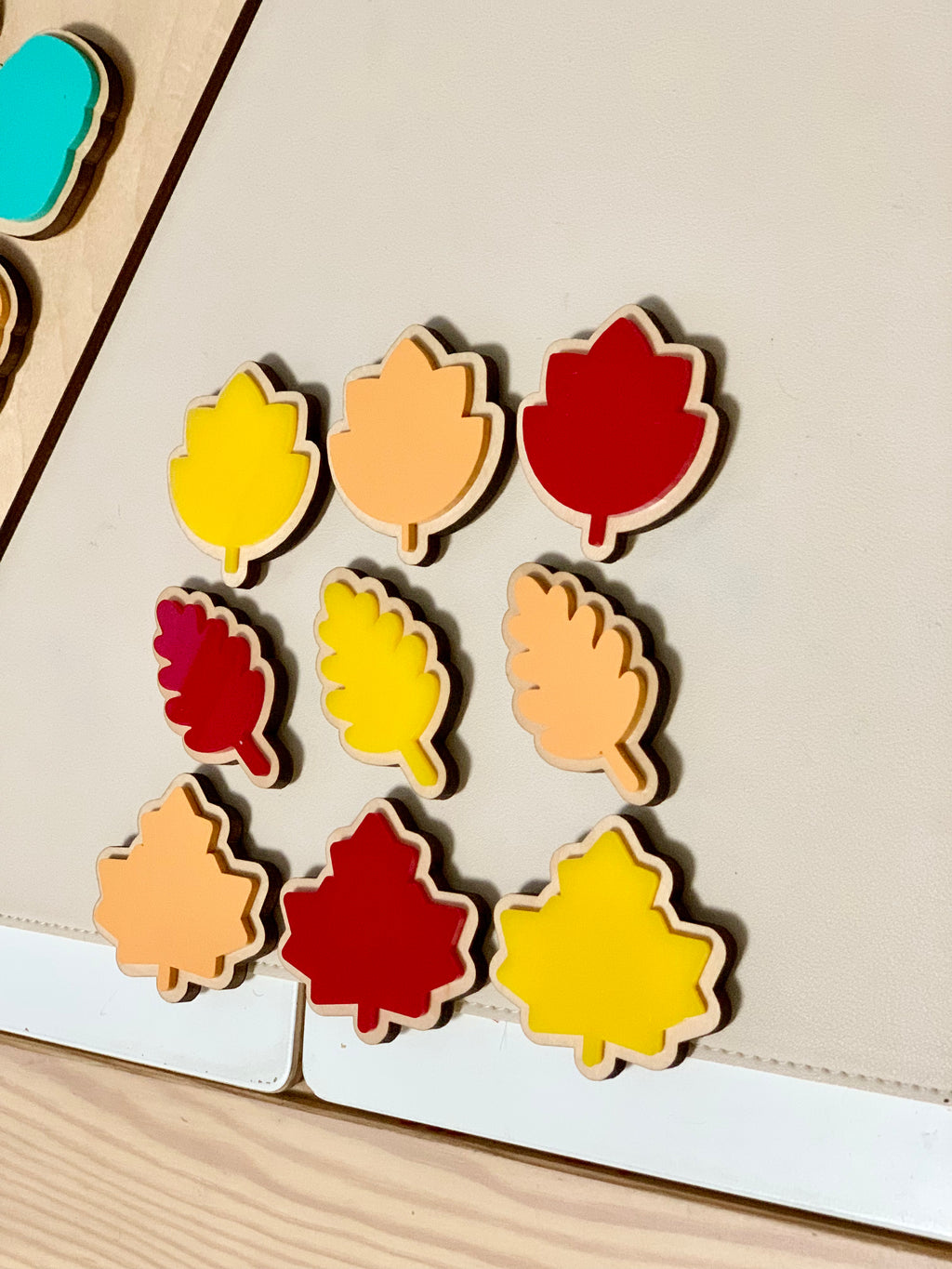 Wooden cookie shapes in red, yellow, and orange with velcro backs arranged on a light cookie sheet surface