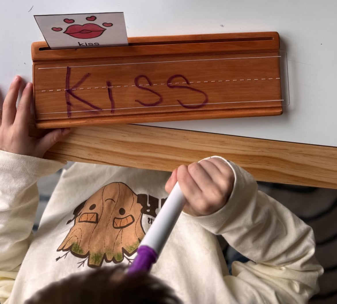 Smaller wooden writing tray with clear dry erase cover and the word KISS written in purple marker on wood surface