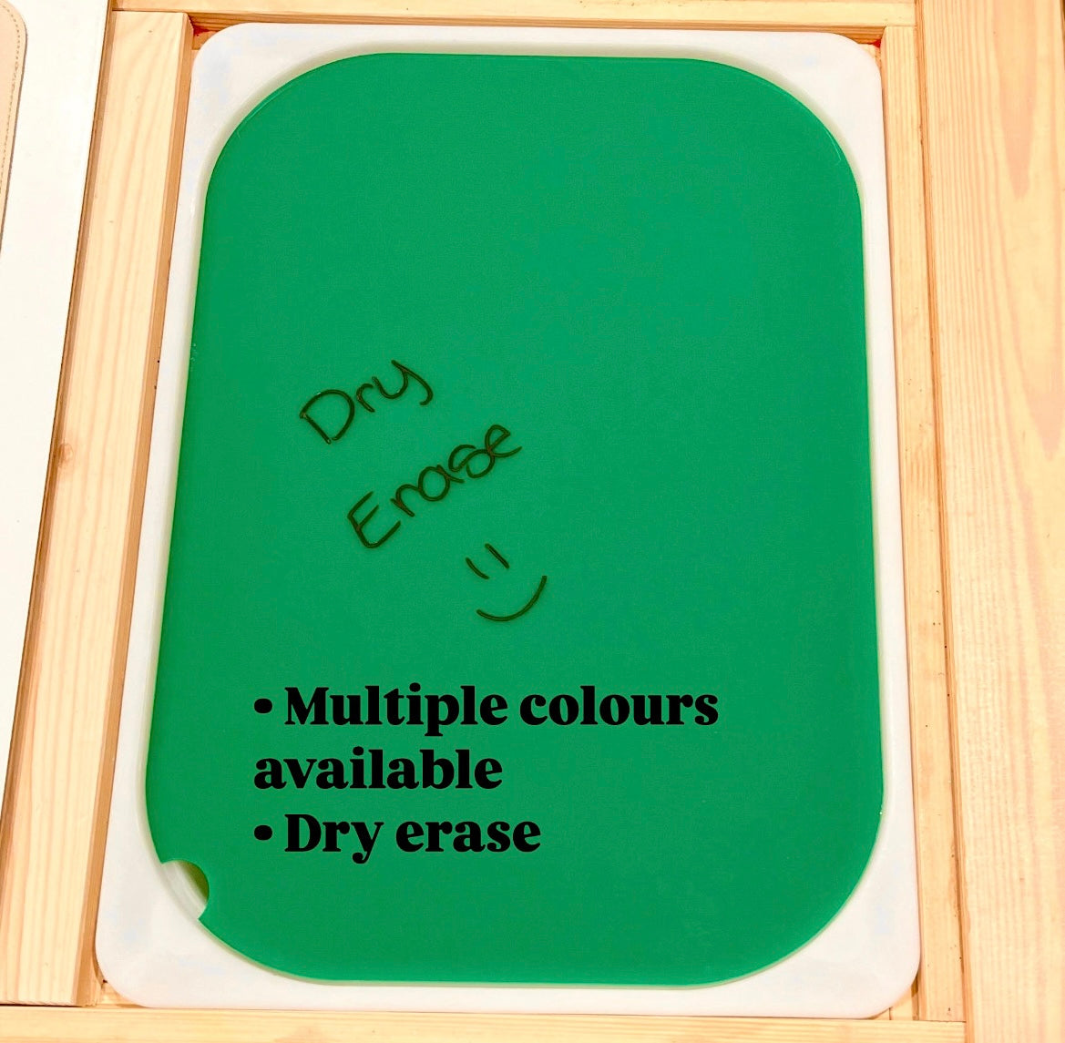 Green dry erase board with rounded corners and handwritten text on a wooden framed surface