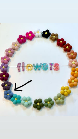 Circular arrangement of colorful handmade felt flowers with colorful glitter letters spelling flowers in the center