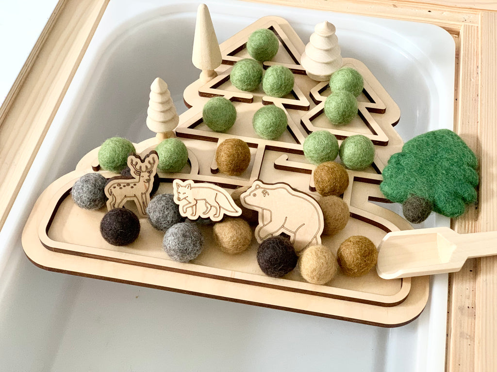 Fillable woodland play tray insert with wooden trees, animal figures, felt balls, and natural wood scoop on white base