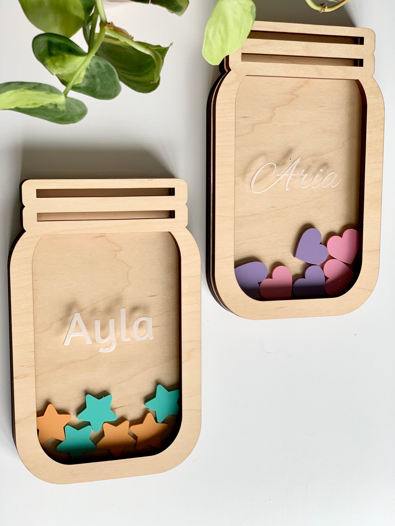 Two personalized wooden reward jars shaped like mason jars, filled with colorful wooden tokens on white surface