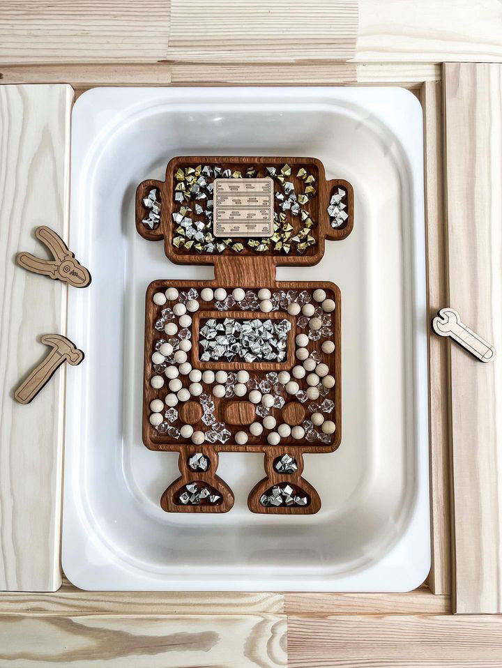 Robot-shaped wooden sensory tray filled with wooden beads, clear crystals, and metallic gems on white background