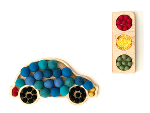 Wooden traffic light sensory tray with red, yellow, and green felt balls and car-shaped tray filled with blue felt balls