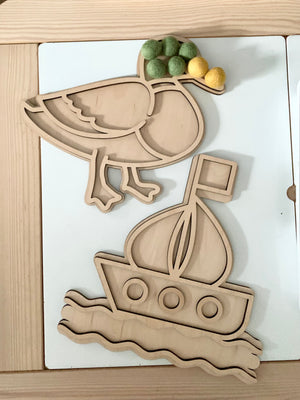 Wooden fillable bird and boat play trays with green and yellow felt balls on light wood and white background